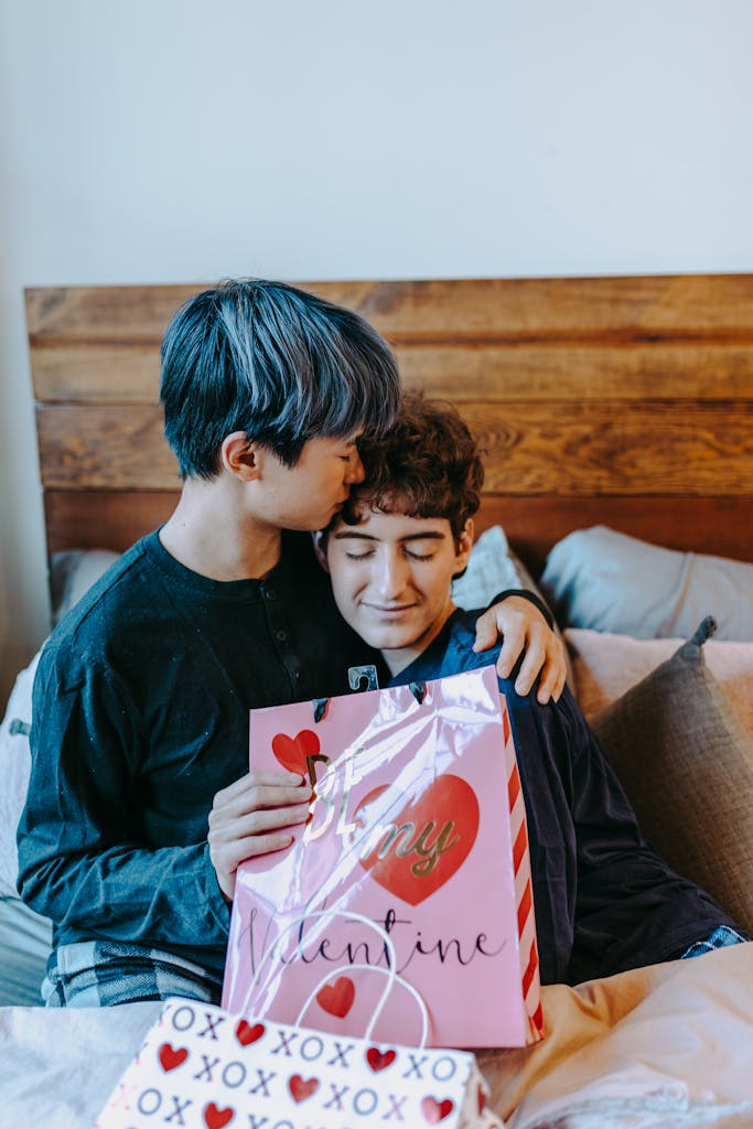 A loving gay couple sharing a tender moment with Valentine's gifts indoors.